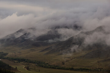 Majestic mountain landscape shrouded in mist, with rolling hills and valleys, creating a serene and...