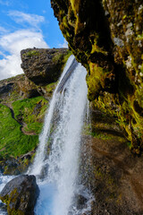 Spectacular waterfall cascading down moss-covered cliffs in Icelands serene landscape