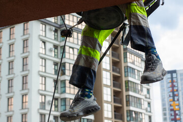 A determined person is climbing up a strong rope in front of a tall building