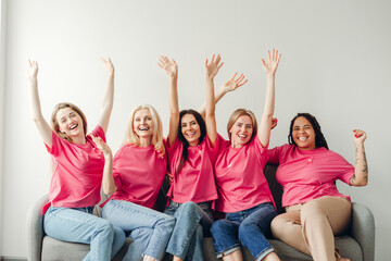 Diverse women raising hands in pink supporting breast cancer awareness