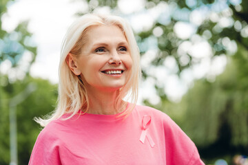 Senior woman smiling and wearing pink ribbon for breast cancer awareness month