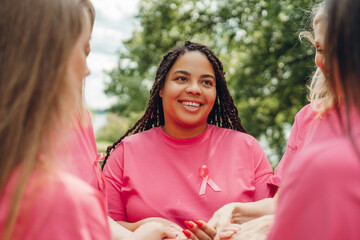 Smiling women holding hands wearing pink ribbons for breast cancer awareness