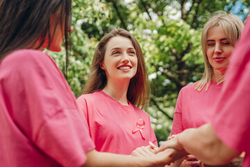Volunteers wearing pink ribbon supporting breast cancer awareness campaign holding hands