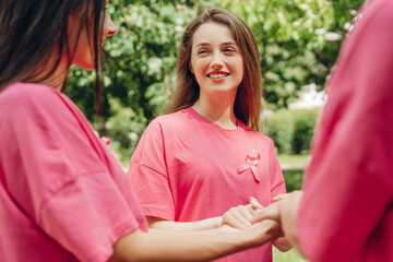 Volunteers holding hands wearing pink ribbons for breast cancer awareness