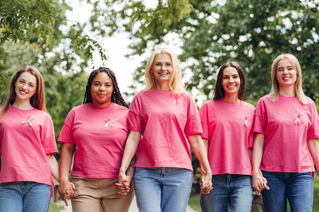 Women holding hands and wearing pink ribbons are walking for breast cancer awareness