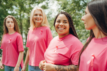Diverse women smiling and supporting breast cancer awareness together outdoors