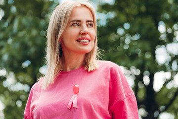 Smiling woman wearing pink ribbon is showing support for breast cancer awareness