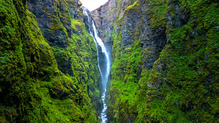 Majestic waterfall cascades down green cliffs in beautiful Icelandic landscape © Fokke Baarssen