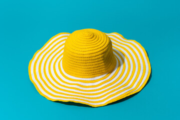 Minimalist photo of striped retro sun wide brim straw hat with harsh shadow. Oversize yellow women...