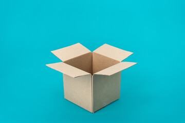 Opened recyclable cardboard box standing on turquoise blue background. Minimalist photo of shipping box. Isometric view of blank packaging, postal, mailing box mock-up with central composition.