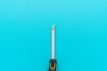 Minimalist overhead photo of tape measure on turquoise blue background with copy space. Flat lay...