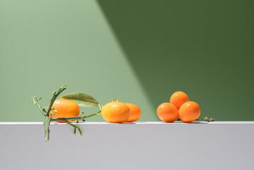 Kumquats naranjas chinas pequeñas sobre un soporte blanco y fondo verde	