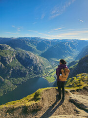 Majestic landscape view from the top of a mountain in Norway with a traveler enjoying nature