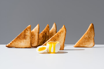 Huevo cocido sobre pan tostado desayuno sobre una mesa blanca y fondo gris
