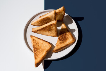Triángulos de pan tostado dorado para sándwiches en un plato blanco sobre un fondo blanco y azul
