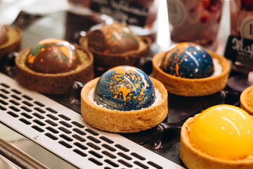 Planet-shaped tartlets with mousse or jelly filling displayed in cafe window.