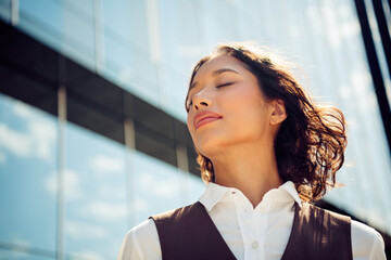Professional businesswoman enjoying a sunny day outdoors, radiating confidence and success against...
