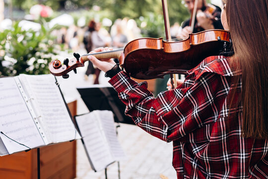 Young female violinist playing street music in the city, outdoor performance.