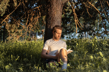 Man reading a book peacefully in a sunny park