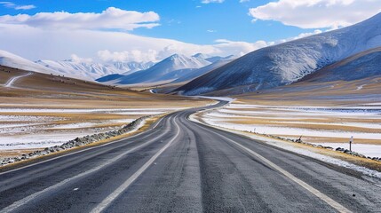 A wide road with beautiful scenery in the snow-capped mountains of northern China, winding roads and white clouds on both sides.