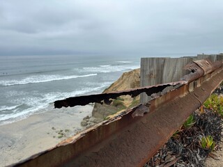 A super rusted guardrail in Carlsbad, California, with a piece of metal visibly bent away,...