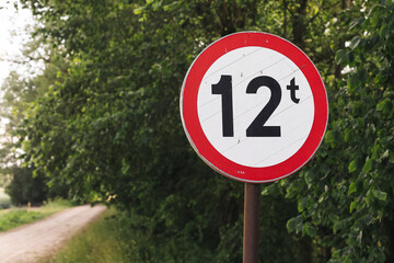 Weight limit road sign 12 tons. Red circular traffic sign on rural dirt road. Vehicle restriction...