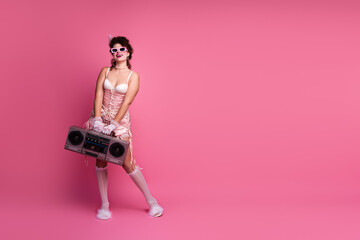 Fototapeta premium A young woman in elegant vintage attire poses against a vibrant pink background, embracing a blend of past and present styles
