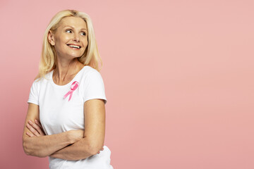 Smiling woman wearing pink ribbon is showing support for breast cancer awareness