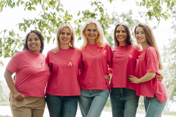 Women wearing pink t-shirts with ribbons are embracing for breast cancer awareness