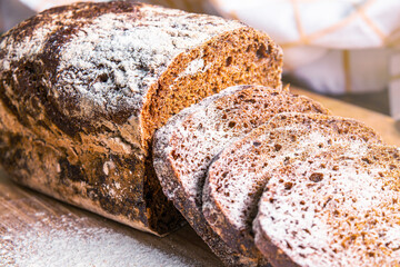 Freshly baked rye bread with sliced pieces displayed on a wooden surface in a cozy kitchen setting