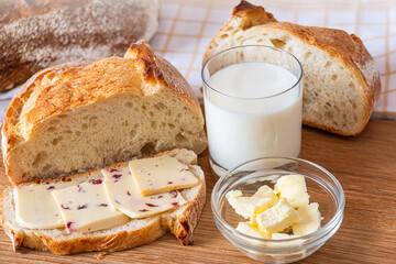 Freshly baked bread with butter and milk served on a wooden table in the morning light