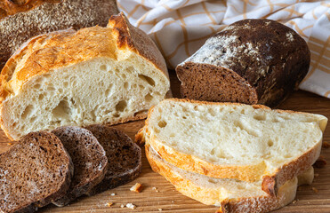 Variety of fresh baked bread displayed on wooden cutting board with cloth in background