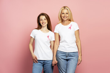 Women wearing pink ribbons holding hands for breast cancer awareness