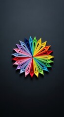 Colorful origami paper arranged in a radiant, circular flower design against a dark background.
