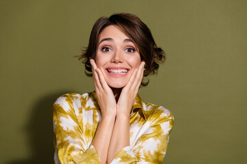 Young woman in elegant blouse smiling brightly against khaki background