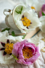 Peony flowers and a cup of tea, books on a white blanket.