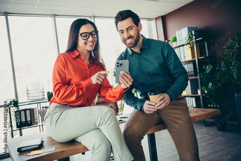 Poster two professionals collaborating in an office setting while reviewing work on a smartphone, demonstra