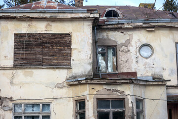
an old, worn-out building facade with several windows and doors, indicating its abandonment or poor condition.