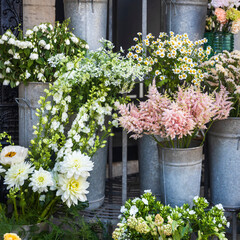 Flowers in white and pink color in galvanized metal buckets displayed outside a flower shop.