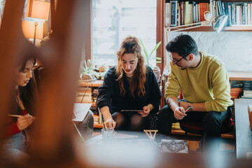 Friends gathered in a warm and inviting home interior engaging in a collaborative discussion. The...
