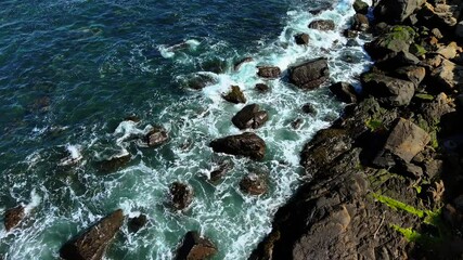 Waves crashing against rocky shoreline. Water splashing over coastal boulders. Ocean surging along jagged seaside rocks - Powered by Adobe