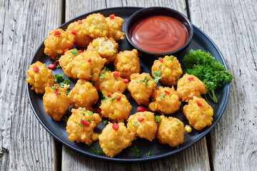 corn nuggets on a plate with tomato sauce