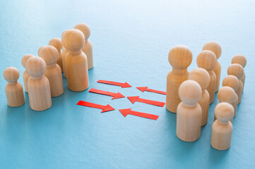 Concept of conflict I war between people or groups. Wooden figures gathered in two groups facing each other.