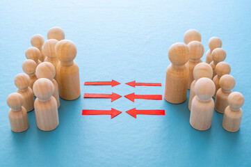 Concept of conflict I war between people or groups. Wooden figures gathered in two groups facing each other.