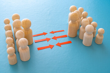 Concept of conflict I war between people or groups. Wooden figures gathered in two groups facing each other.