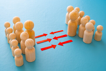 Concept of conflict I war between people or groups. Wooden figures gathered in two groups facing each other.