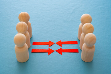 Concept of conflict I war between people or groups. Wooden figures gathered in two groups facing each other.