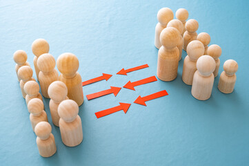 Concept of conflict I war between people or groups. Wooden figures gathered in two groups facing each other.