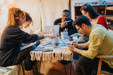 Group of people engaged in a creative painting workshop indoors, focusing on artistic projects and...