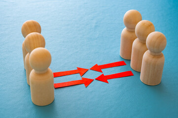 Concept of conflict I war between people or groups. Wooden figures gathered in two groups facing each other.